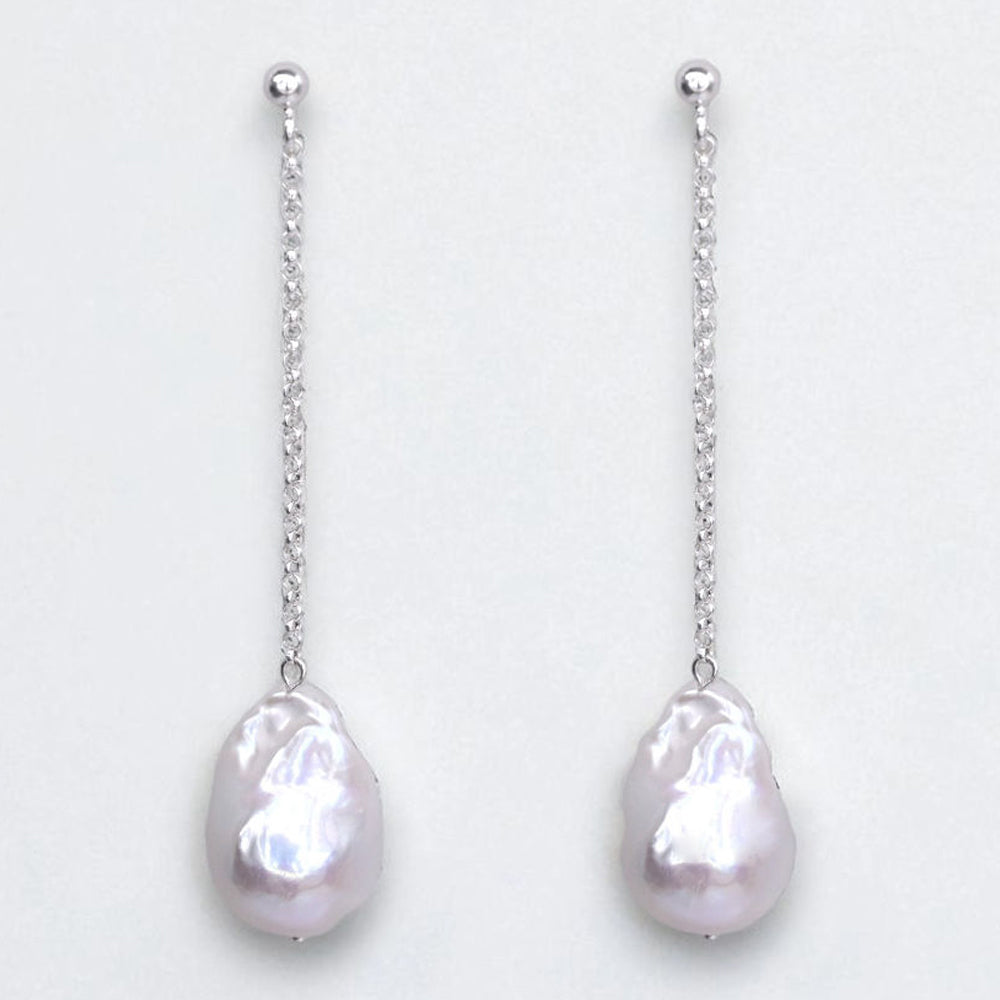 Baroque pearl earrings with silver chains on a light gray background
