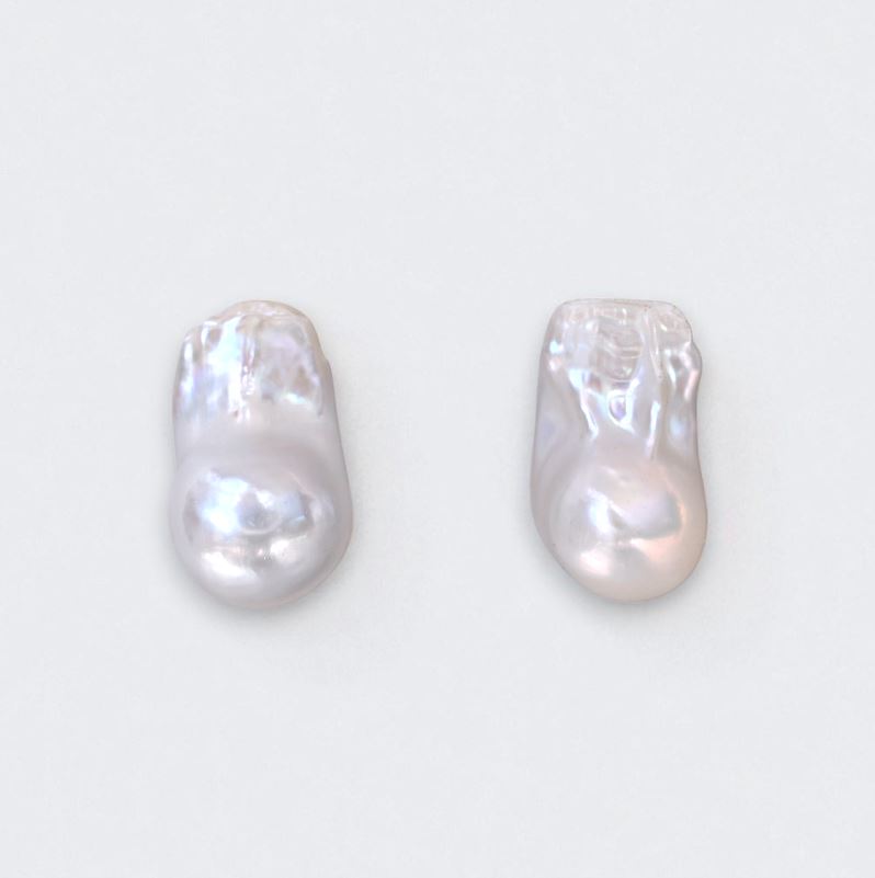 Two white natural baroque pearls on a light gray background