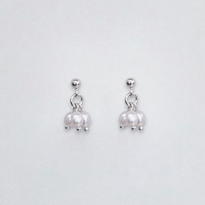Pair of natural white pearl sterling silver earrings on a light gray background