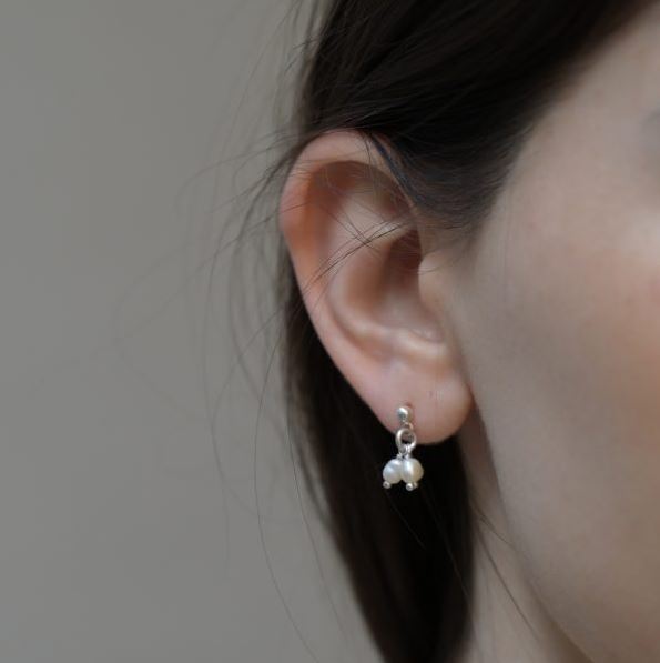 Woman wearing natural white freshwater pearl silver earrings