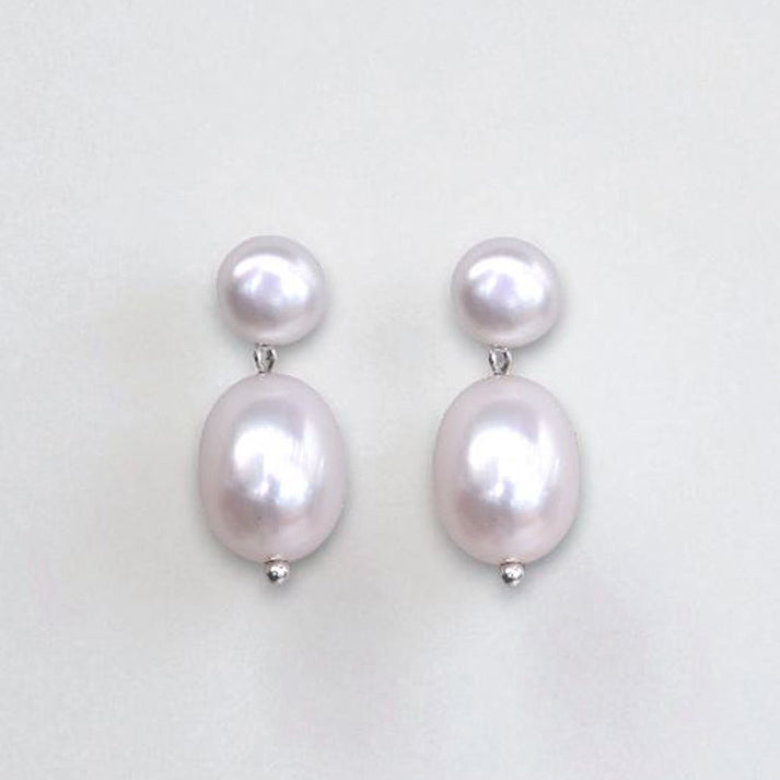 Pair of natural white pearl earrings on a light gray background