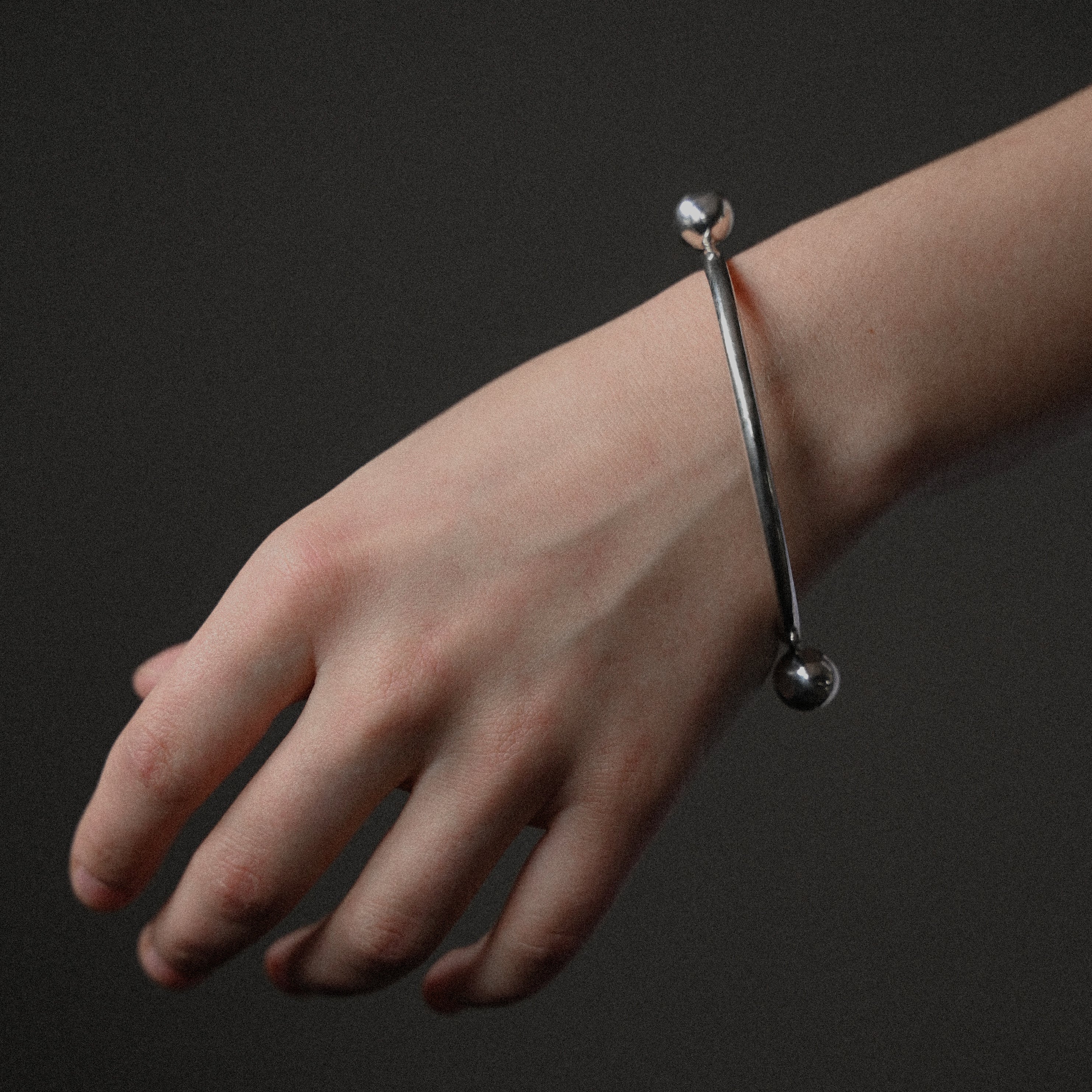 Hand wearing sterling silver bangle on a dark background