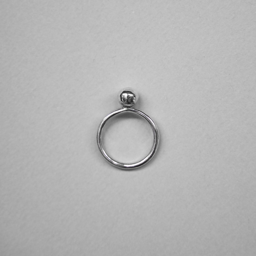 Silver ring with a spherical top on a gray background