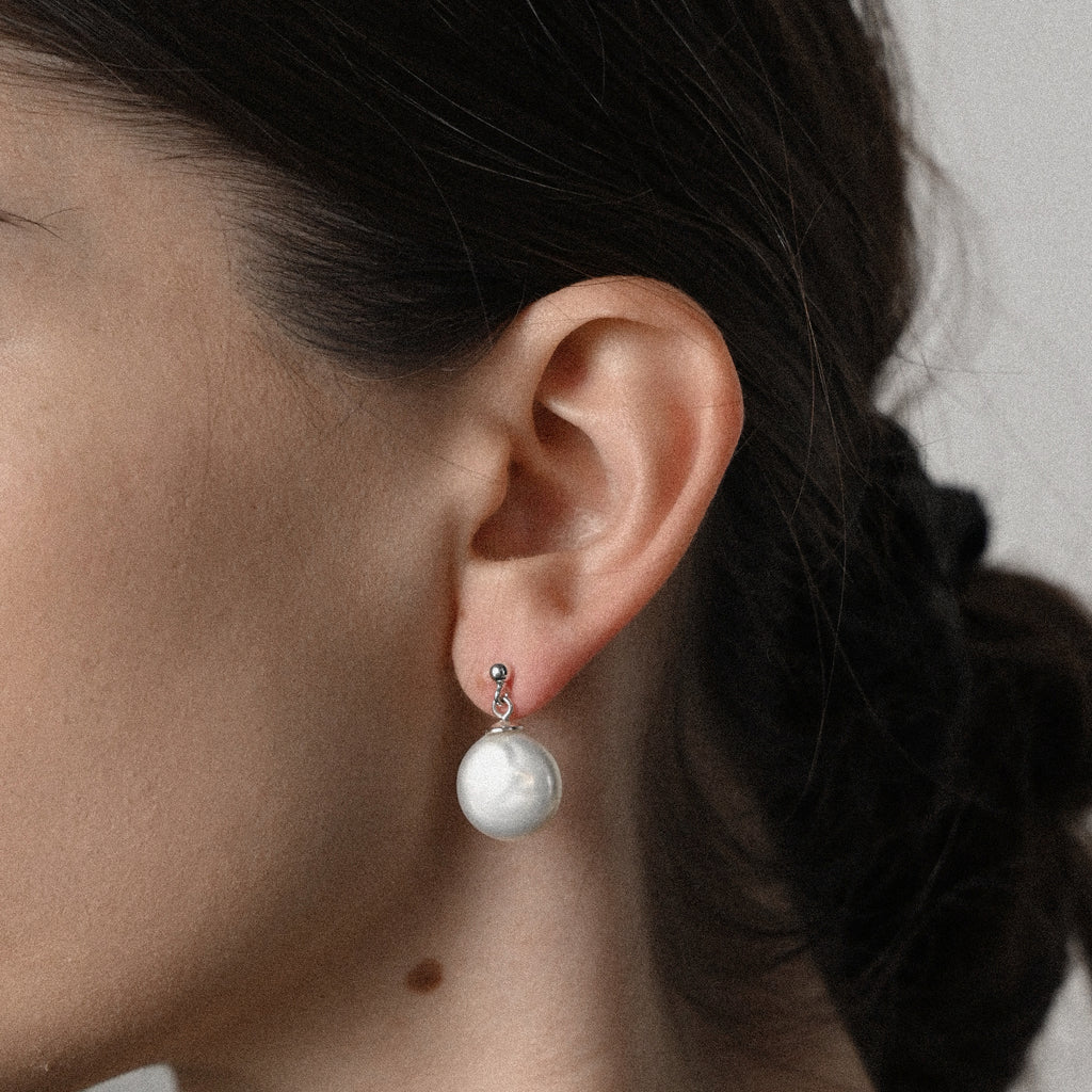 Close-up of an ear wearing a white pearl earring.