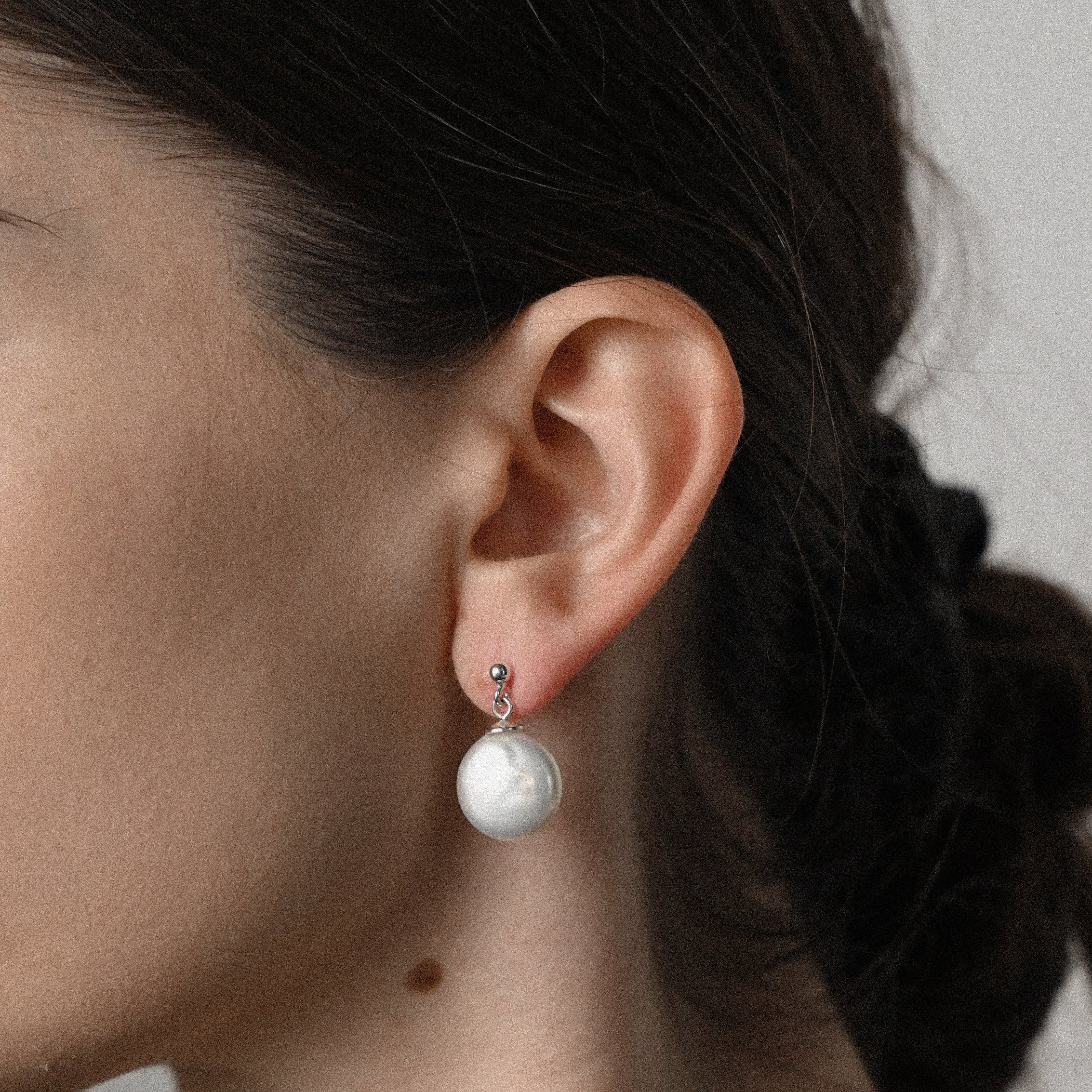Close-up of an ear wearing a white pearl earring.